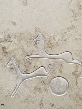 Close-up of the finished relief of horses leaping around a circular sun or moon form