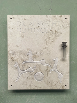 Columbarium plaque made of Jurassic limestone with horse relief on green background