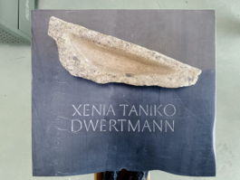 Nahaufnahme eines Grabsteins aus irischem Kalkstein mit der eingravierten Aufschrift. Obenauf liegt eine kleinere Sandsteinskulptur, die vom Vater der Verstorbenen geschaffen wurde und mit Wasser gefüllt werden kann, bis sie überläuft.