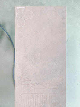 Early working stage of the gravestone showing drawn architectural outlines on the marble surface